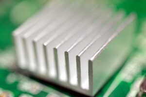 A selective focus closeup of an aluminum heatsink cooler on a green computer circuit board