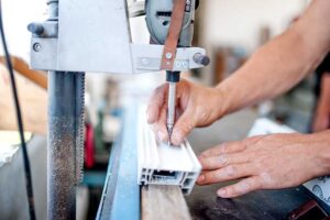 closeup of a worker using manufacturing equipment on a piece of extruded aluminum for making doors and windows